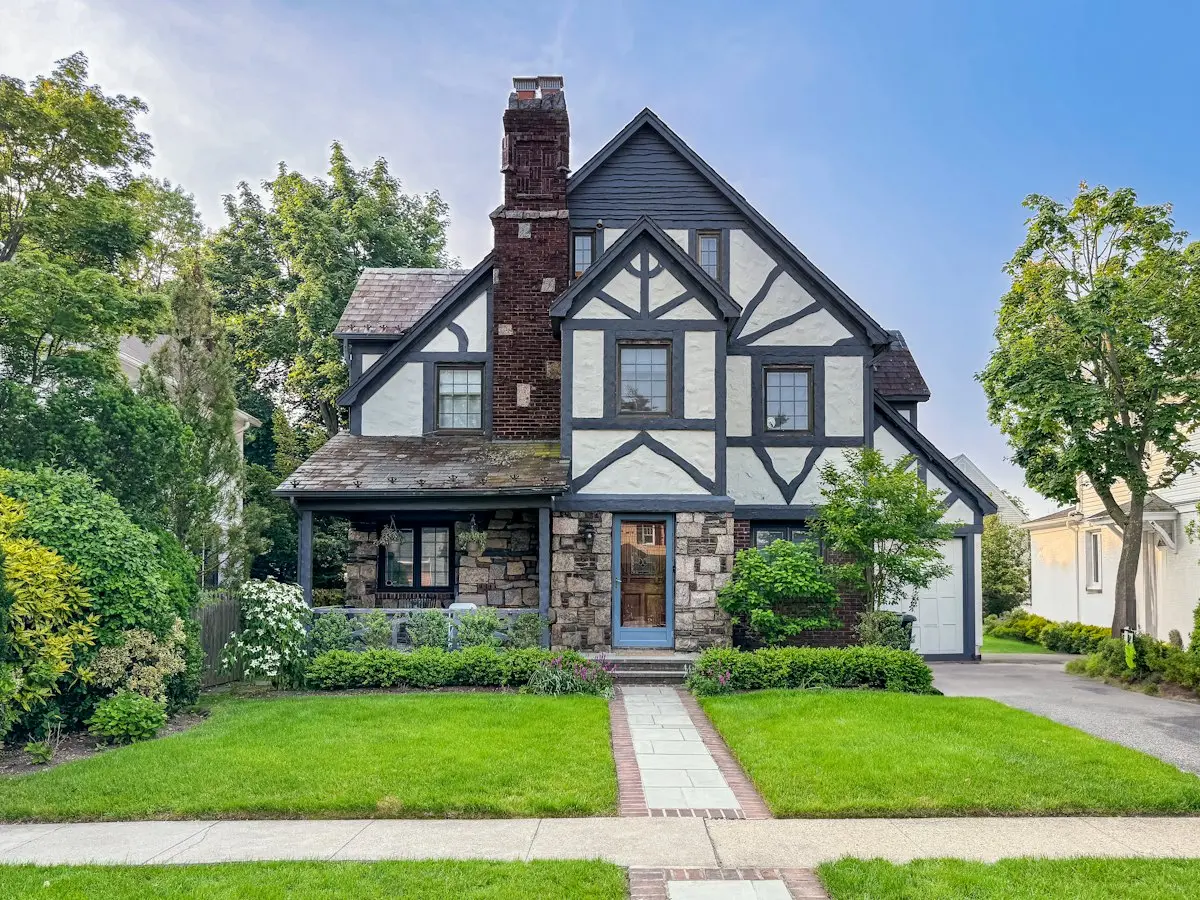 Tudor style home with a clean lawn, stone path and layered shrubs